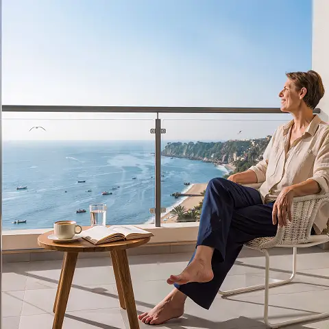 Seniorin auf Balkon mit Meerblick genie&szlig;t die Sonne