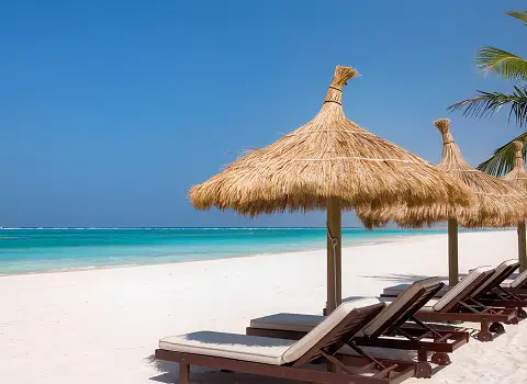 Wei&szlig;er Sandstrand auf Djerba mit Sonnenliegen und Palmen, t&uuml;rkisfarbenes Meer.