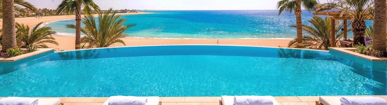 Infinity-Pool eines Strandhotels in Mahdia mit direktem Blick auf das t&uuml;rkisblaue Meer und Palmen